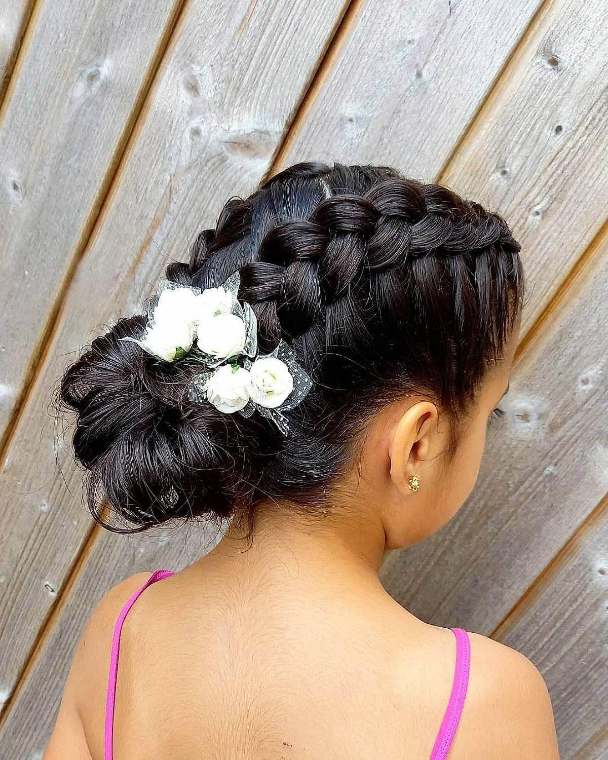 Coiffure pour filles avec tresses et chignon bas avec accessoire en fleurs