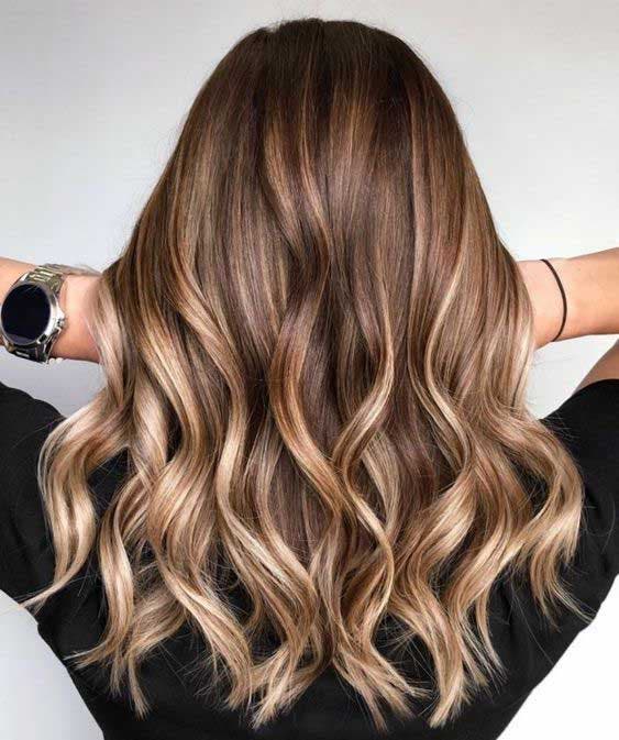 Balayage blond foncé sur cheveux longs et ondulés