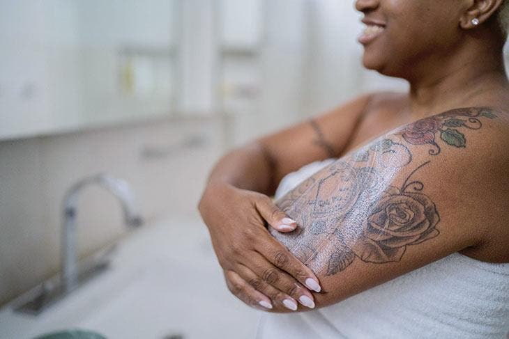 Femme appliquant une crème hydratante sur le tatouage