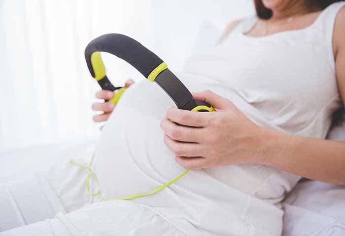 Femme enceinte qui fait écouter de la musique à son bébé