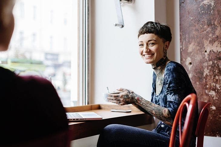 Femme tatoué tenant une tasse de café