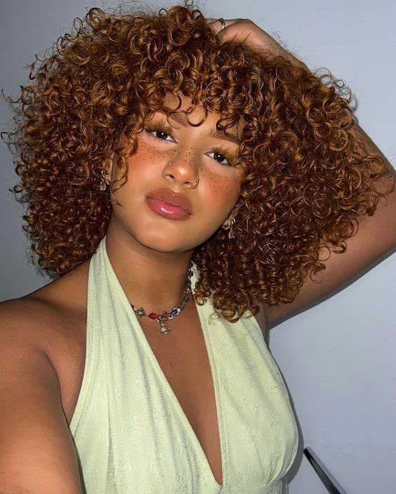 Look afro avec coupe dégradée sur cheveux mi-longs avec coloration cuivrée