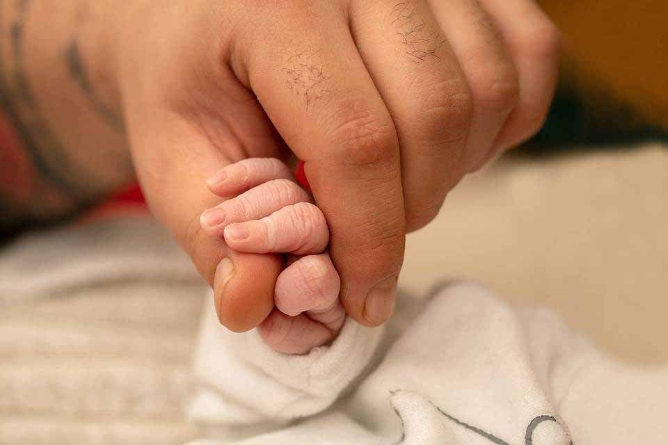Main d’adulte tenant la main d’un nouveau-né