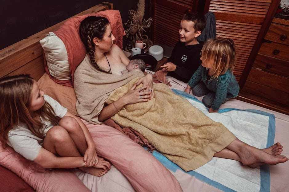 Maman allaitante entourée de ses enfants
