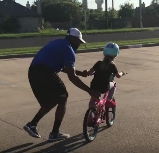 Myke Rousell en train d’apprendre à sa fille à faire du vélo