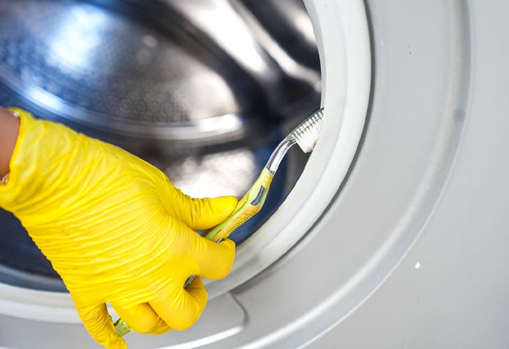 Nettoyage des joints de la porte de la machine à laver avec une vieille brosse à dents