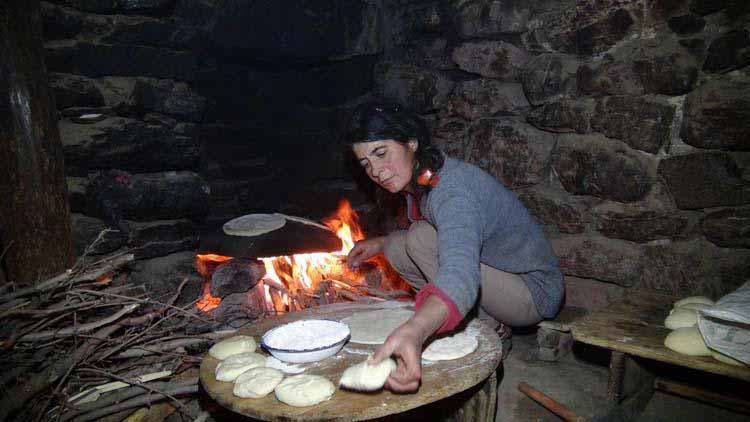 Photo de l’une de femme de la tribu en train de préparer du pain avec du feu de bois