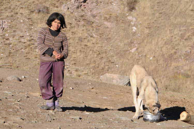 Photo de l’une des femmes de la tribu avec un chien qui mange dans sa gamelle
