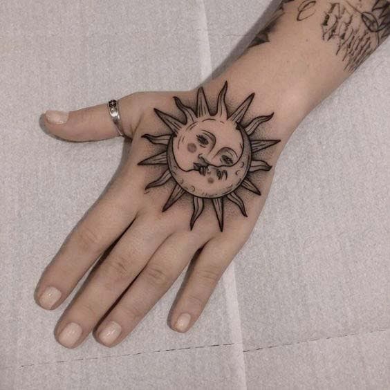 Tatouage soleil avec visage sur la main