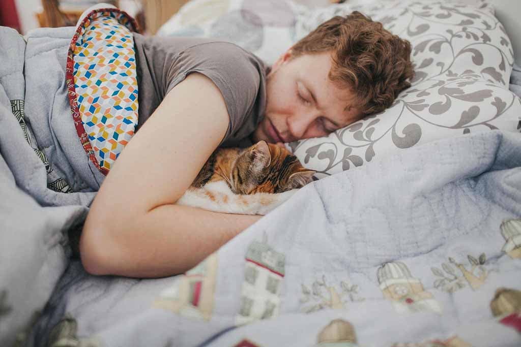Un homme qui dort avec son chat
