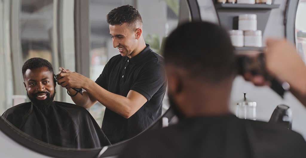 Un homme se faisant couper les cheveux par son coiffeur