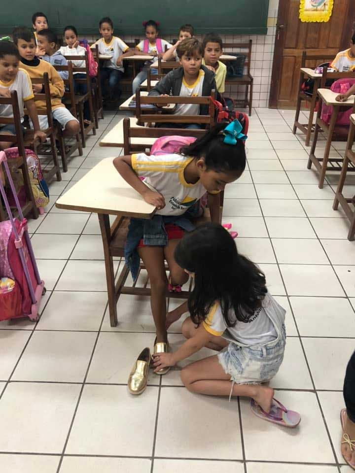 Une élève donne ses chaussures à une camarade