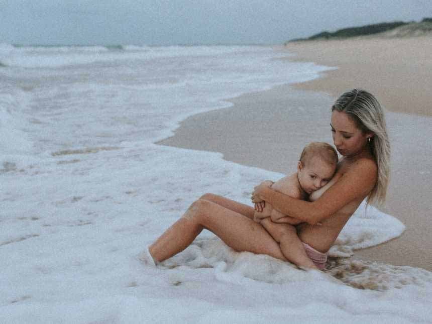 Une maman allaite son enfant au bord de la plage