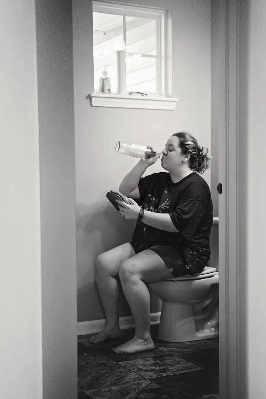 Une maman qui regarde sa tablette dans les toilettes