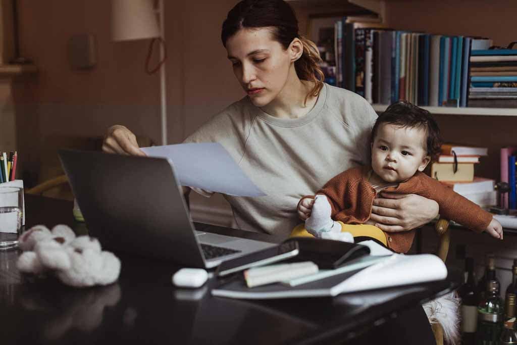 Une maman qui travaille et porte son enfant dans ses bras