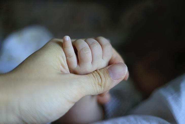 Une maman tient la main de son nouveau-né