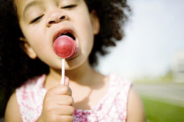 A little girl eats a lollipop