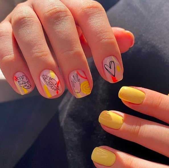 Vernis à ongles jaune sur la main gauche et motifs variés sur la main droite