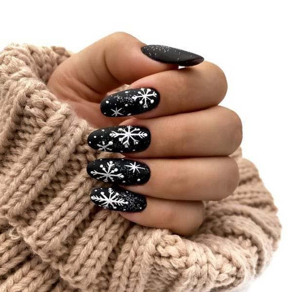 Des ongles en noir avec des motifs en blanc 