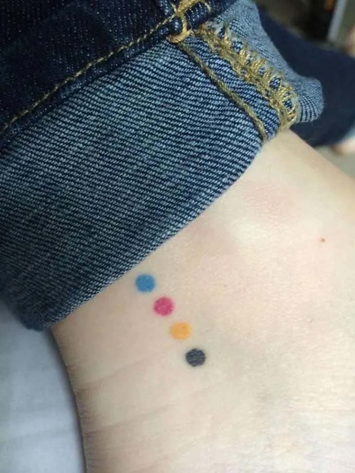 Tatouage de quatre points de couleurs différentes sur la cheville