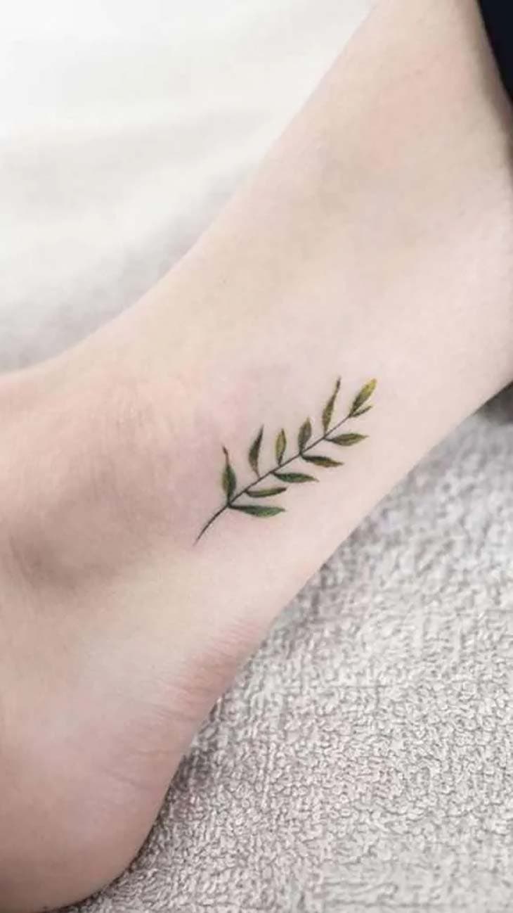 Petite branche fine avec feuilles vertes, tatouée sur la cheville