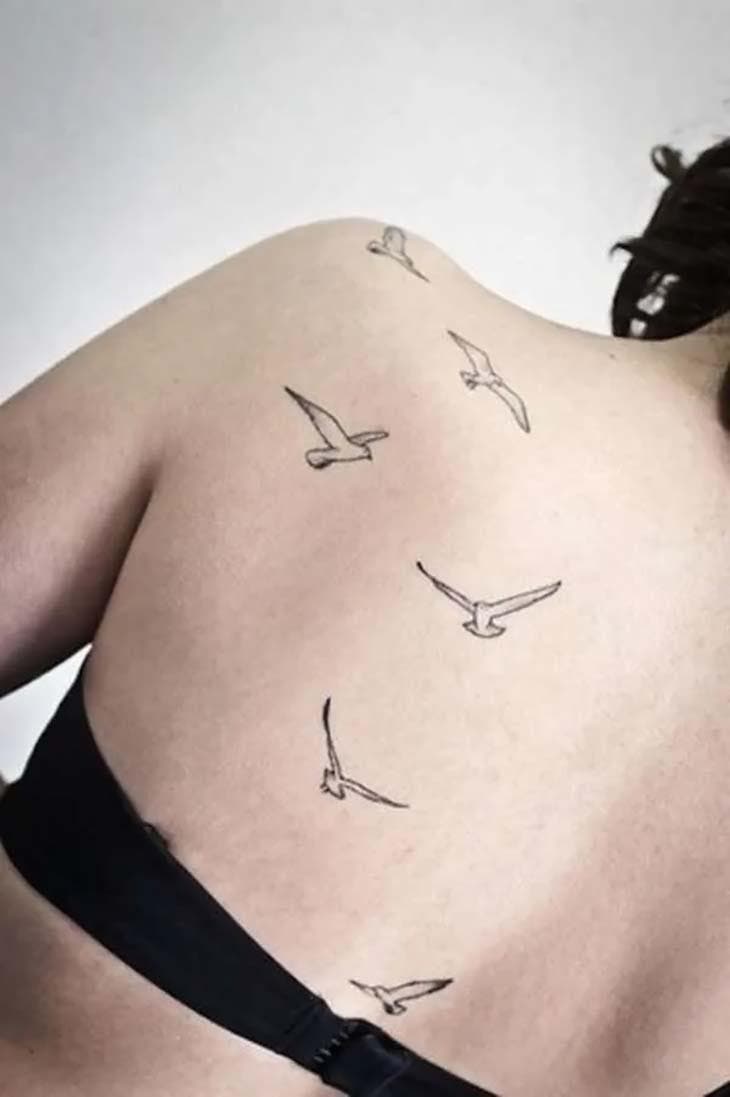 Tatouage d’oiseaux volants sur le dos d’une femme