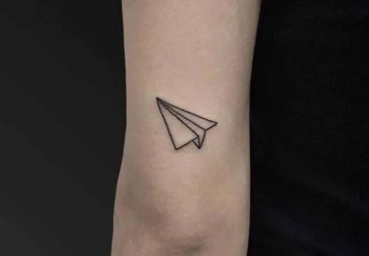 Tatouage d’un avion en papier à l’arrière du bras