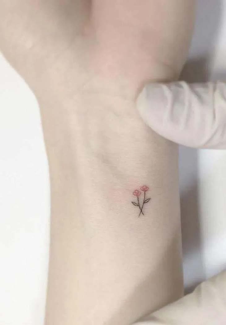 Tatouage de deux mini fleurs colorées sur le poignet. 