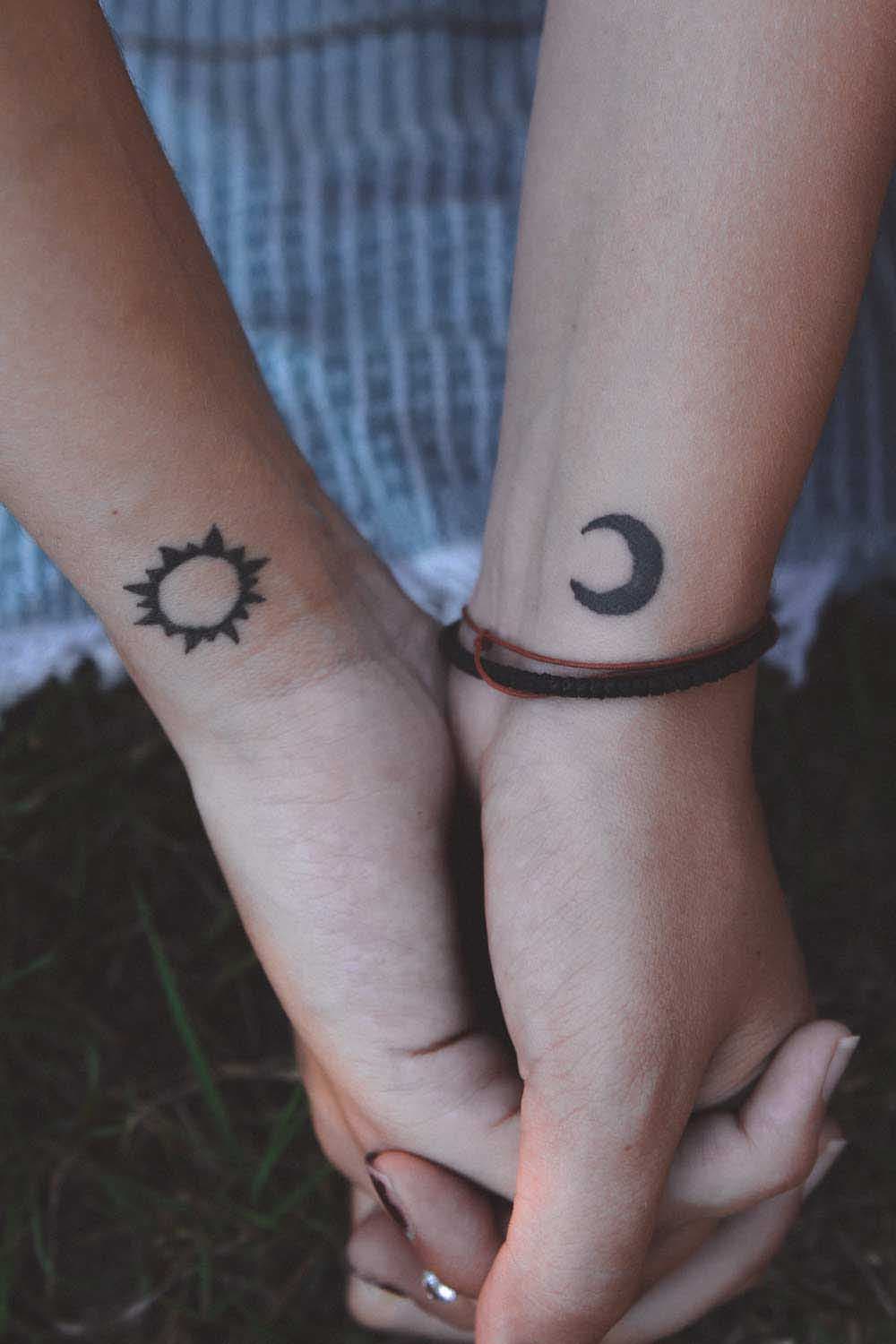 Petits tatouages représentant la lune sur une main et le soleil sur l’autre main du partenaire
