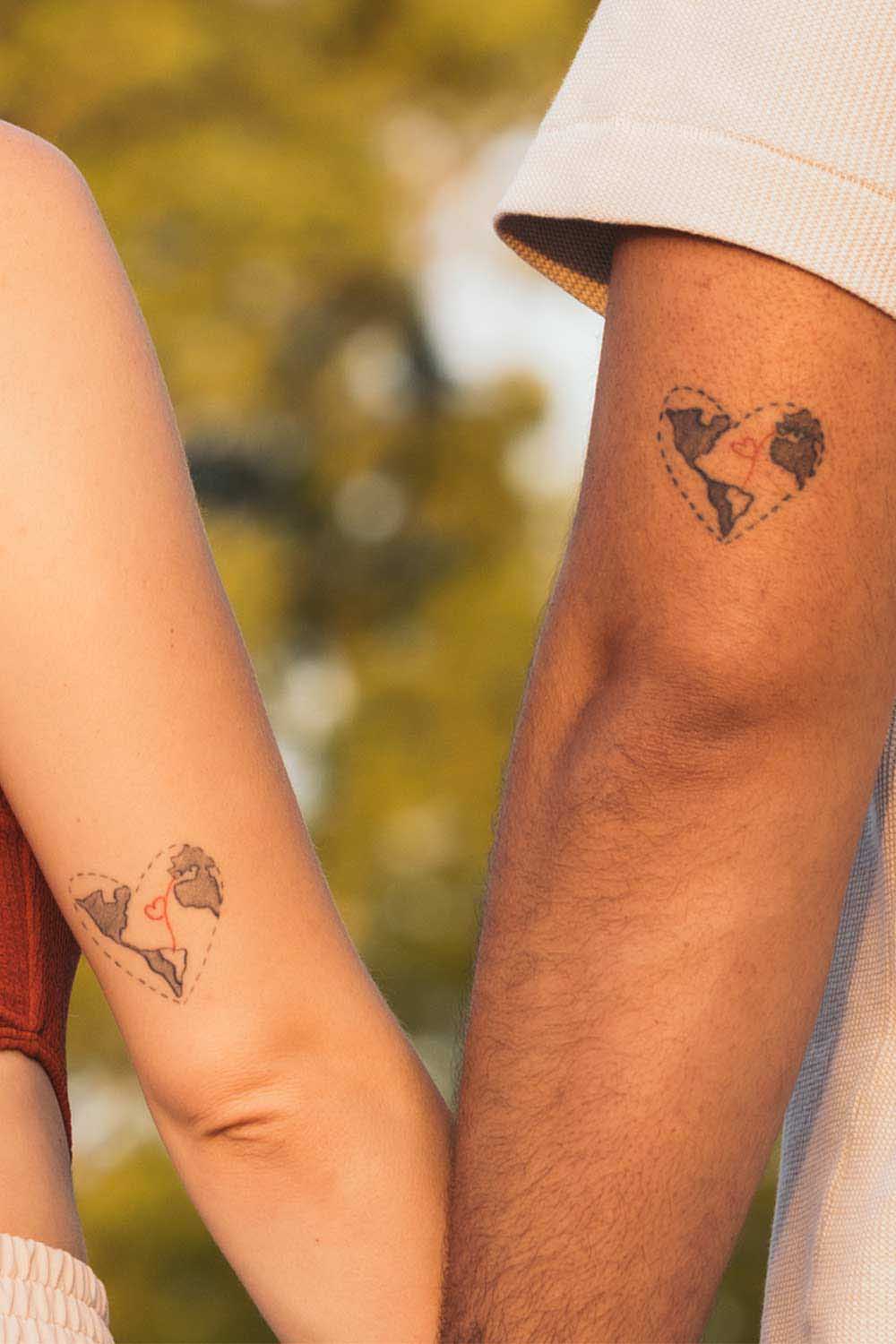 Deux tatouages représentant la carte du monde avec un petit cœur qui relie les pays des deux partenaires