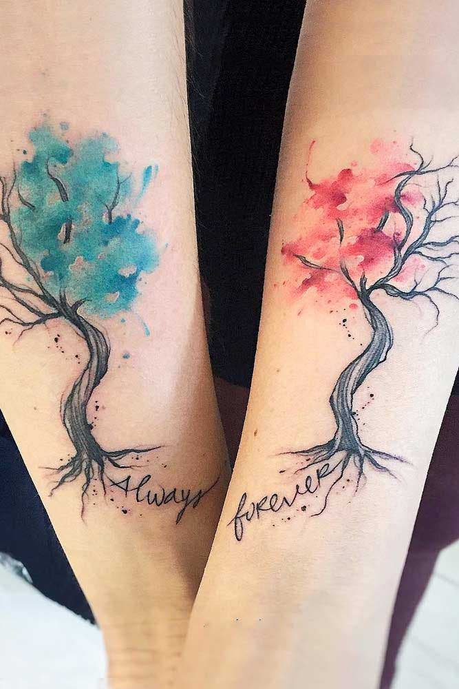 Deux tatouages représentant des arbres avec une touche d’aquarelle rose et bleu et les mentions “toujours” et “à jamais”