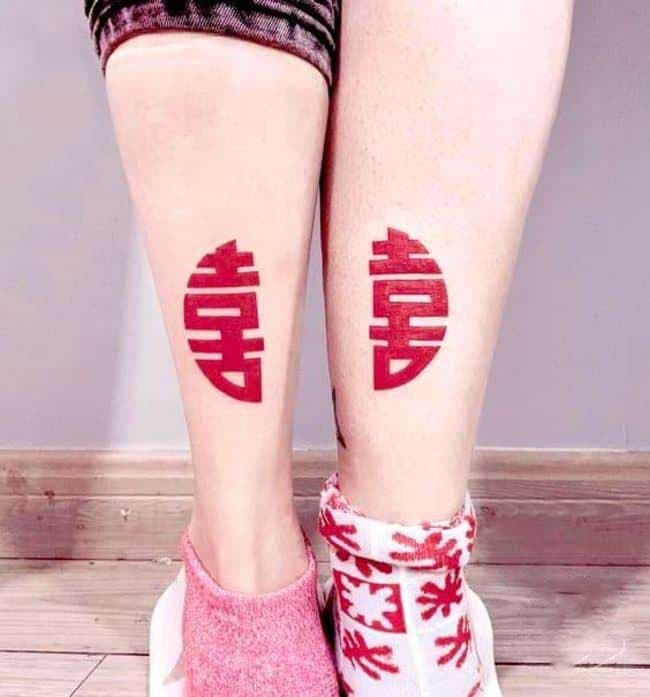 Deux tatouages représentant des caractères chinois, qui une fois mis ensemble signifient “bonheur”