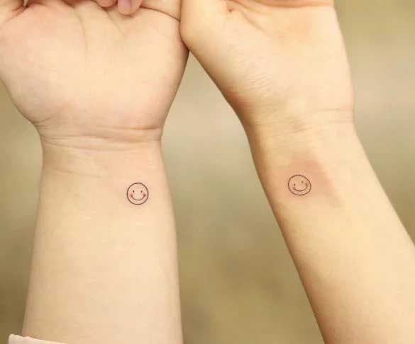 Deux tatouages minimalistes similaires représentant deux petits smileys