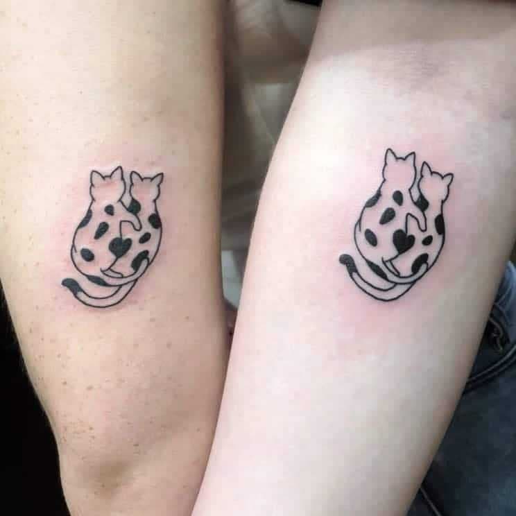 Deux tatouages similaires représentant deux chats qui s’entrelacent