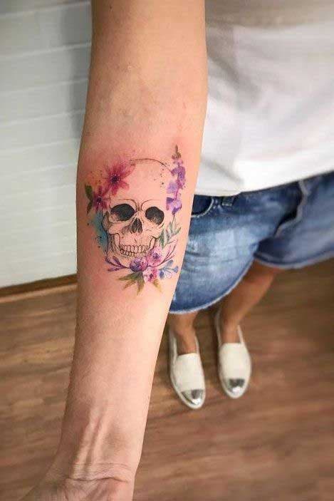 Tête de mort et fleurs en tatouage sur l’avant bras