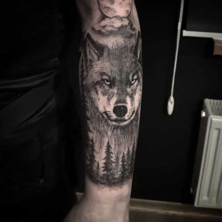 Tatouage d'avant-bras de loup entre les arbres 